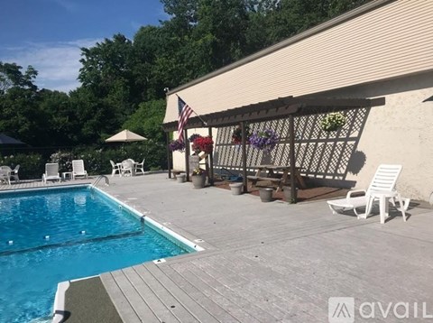 A pool area with a wooden deck and a covered patio.