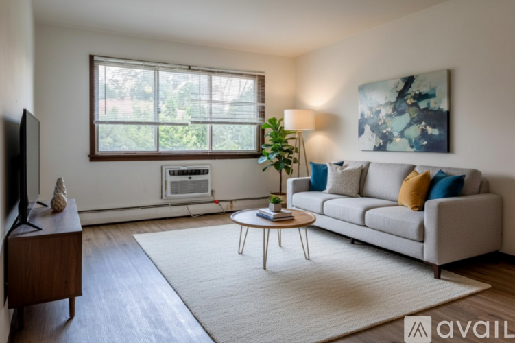 A living room with a white couch, a wooden cabinet, a flat screen TV, a plant, and a painting on the wall.