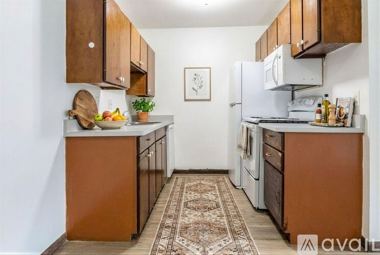 A kitchen with brown cabinets and a rug on the floor.