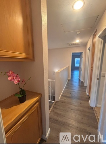 A hallway with wooden floors and a flower on a cabinet.