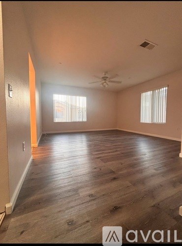 A spacious room with wooden flooring and a ceiling fan.