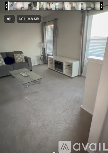 A living room with a grey couch and a glass coffee table.