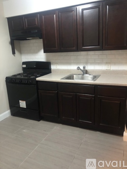 A kitchen with dark brown cabinets and a black stove top oven.