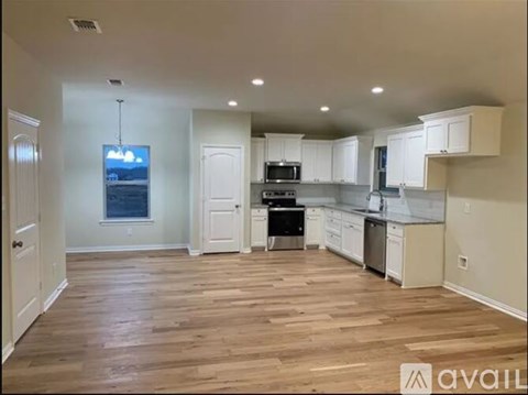 A kitchen with white cabinets and a wooden floor.