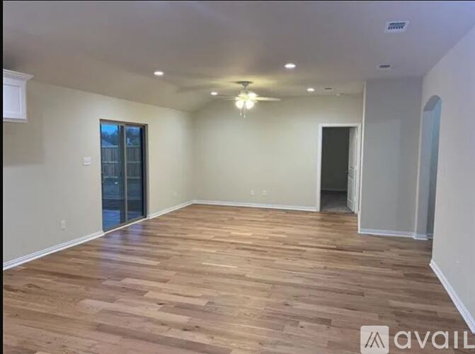 A spacious room with wooden flooring and a ceiling fan.