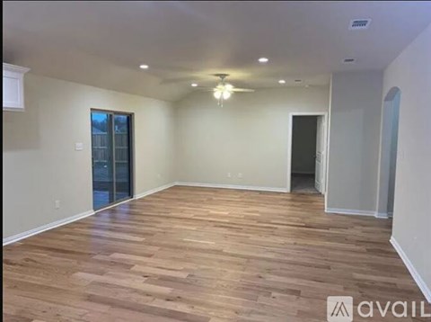 A spacious room with wooden flooring and a ceiling fan.