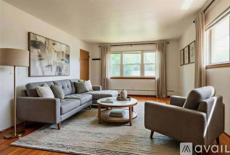 A living room with a grey sofa, a grey armchair, a coffee table, and a large painting on the wall.