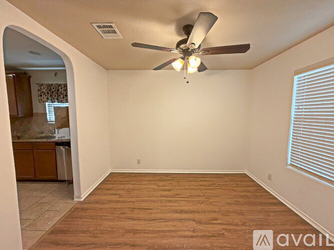 A room with a ceiling fan and wooden flooring.