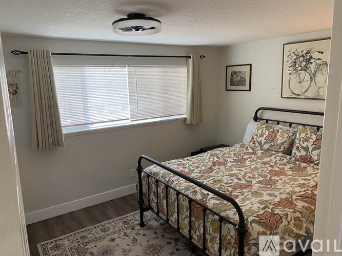A bedroom with a bed, a window with curtains, and a framed picture of a bicycle on the wall.