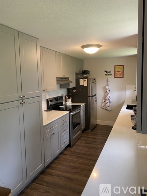 A kitchen with white cabinets and a wooden floor.