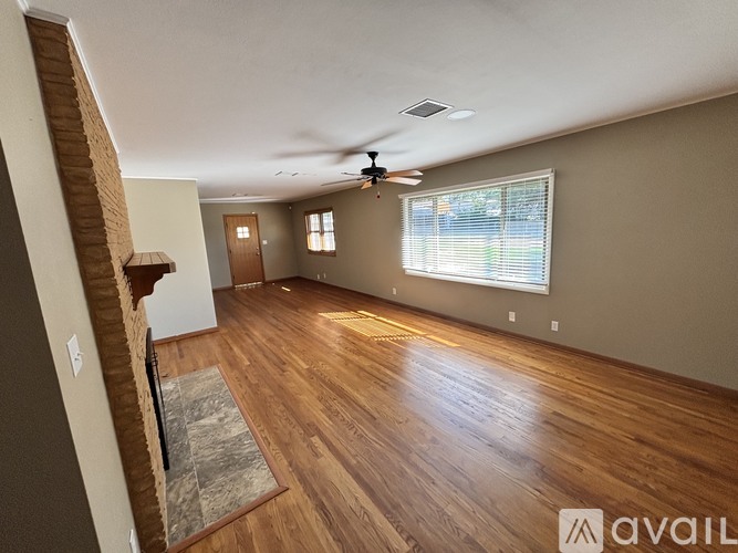 A spacious room with wooden floors and a ceiling fan.
