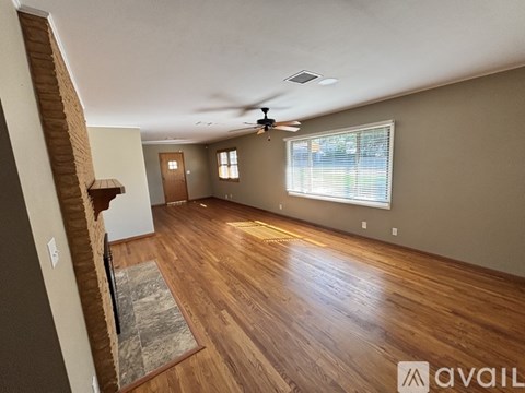 A spacious room with wooden floors and a ceiling fan.