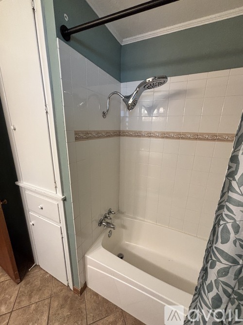 A white bathtub with a shower head and a grey shower curtain.