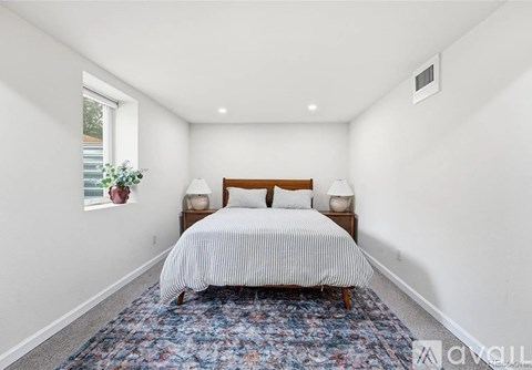 A bedroom with a bed, two lamps, and a window.