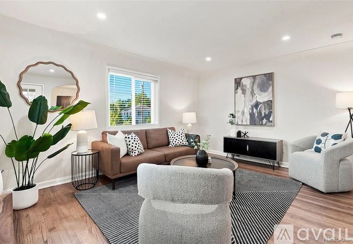 A living room with a grey sofa, a white armchair, a wooden coffee table, and a large mirror on the wall.