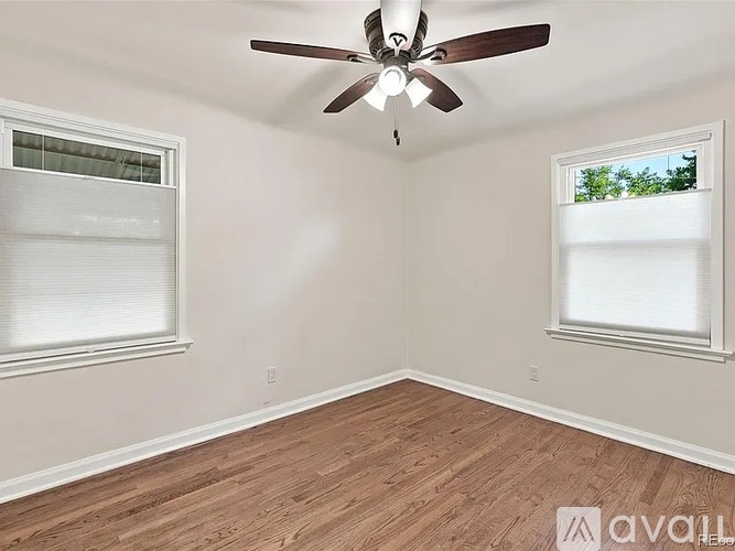 A room with a ceiling fan and two windows.