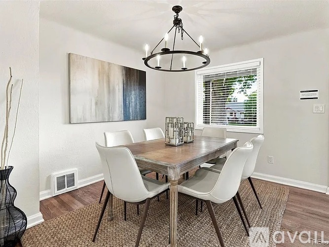 A dining room with a wooden table and white chairs.
