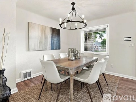 A dining room with a wooden table and white chairs.