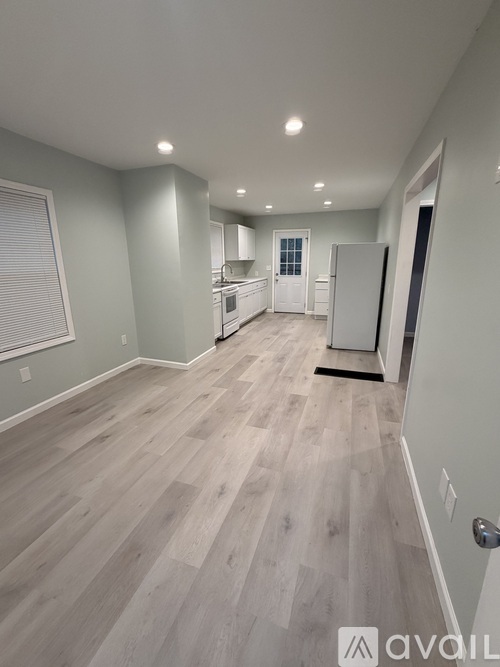 A spacious kitchen with light wood flooring and white appliances.