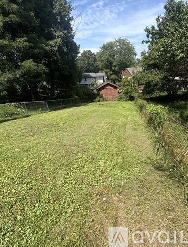 A grassy field with a fence and trees in the background.