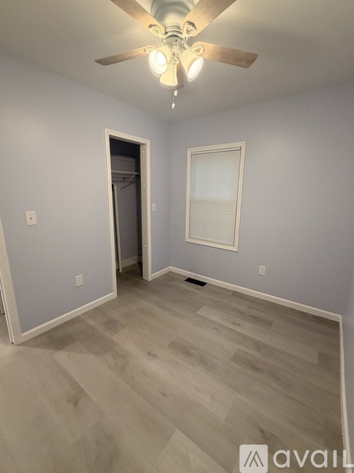 A room with a ceiling fan and light fixture, and a doorway leading to another room.
