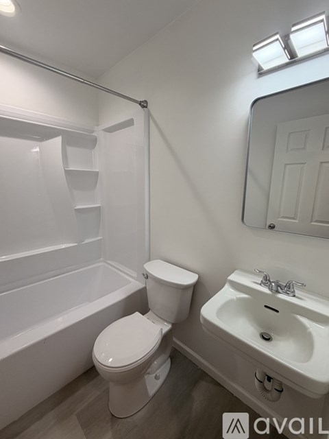 A white toilet sits next to a white sink in a small bathroom.