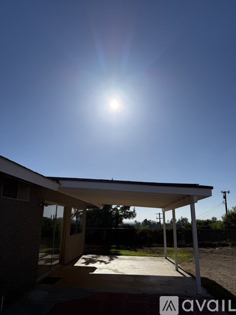 A carport with the sun shining brightly in the background.