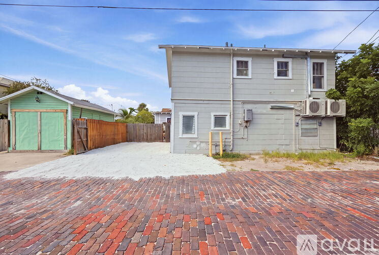 A house with a grey exterior and a red brick driveway.