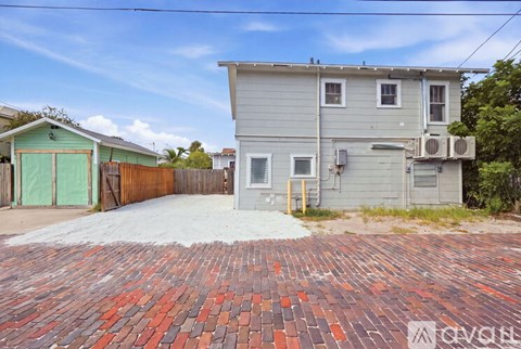 A house with a grey exterior and a red brick driveway.