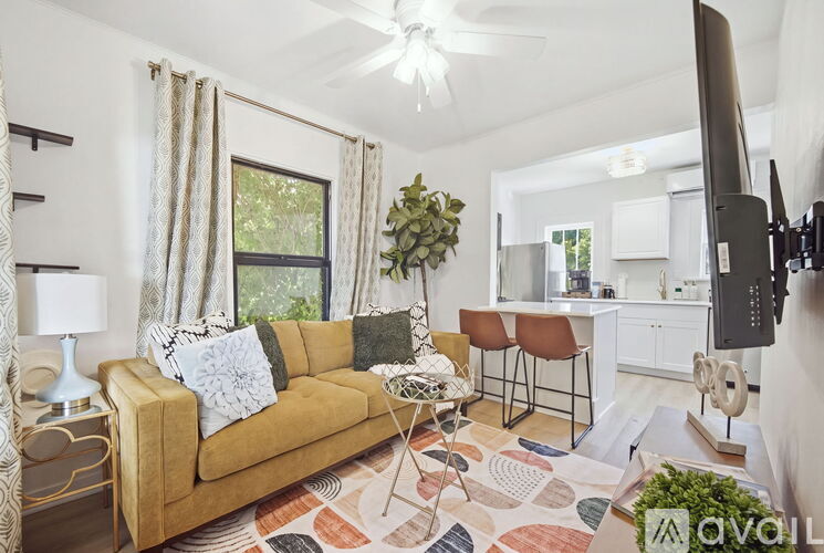 A living room with a tan couch and a television on the wall.