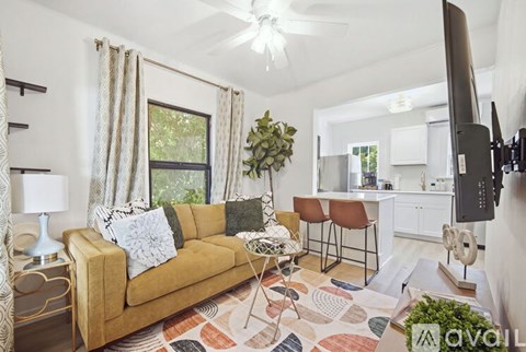 A living room with a tan couch and a television on the wall.