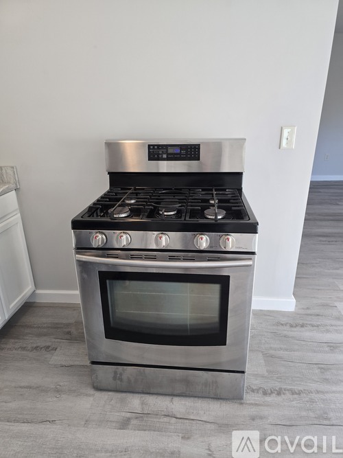 A modern stainless steel gas range with an oven in a kitchen.