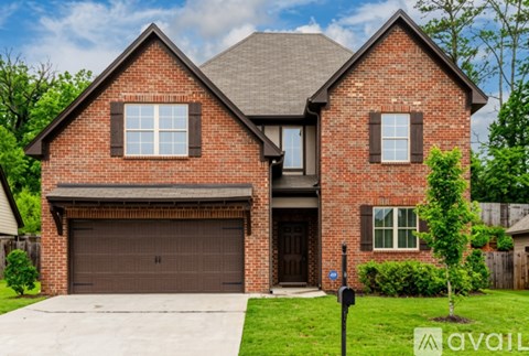 A two-story brick house with a garage and a driveway.