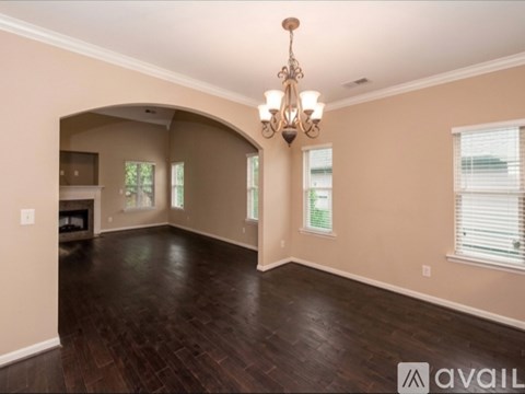 A spacious room with a chandelier and hardwood floors.