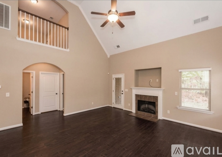 A spacious living room with a fireplace and a ceiling fan.