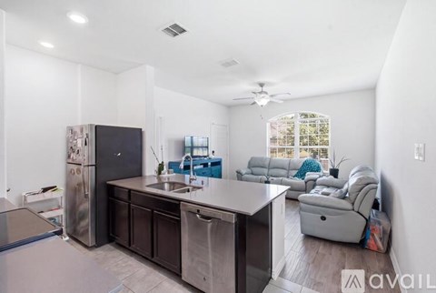A kitchen with a refrigerator, sink, and a dining table with chairs.