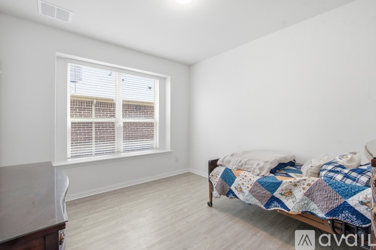 A bedroom with a bed, a chair, and a window with blinds.