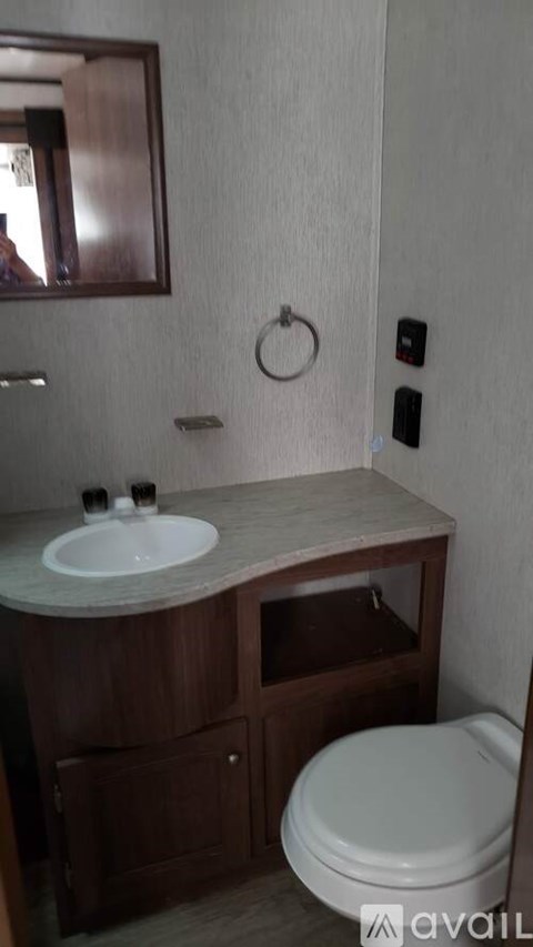 A bathroom with a toilet, sink, and mirror.
