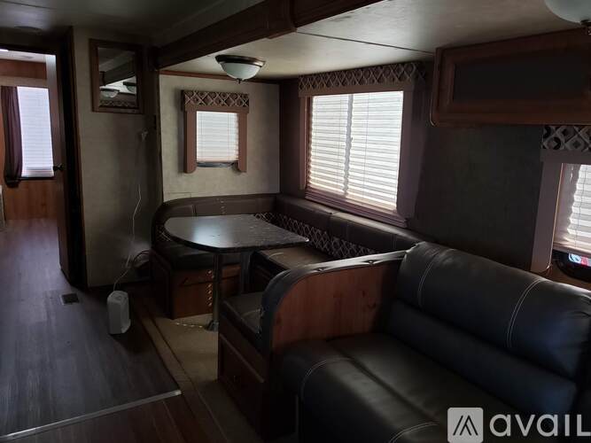 A living room with a black leather couch and a wooden table.