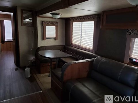 A living room with a black leather couch and a wooden table.