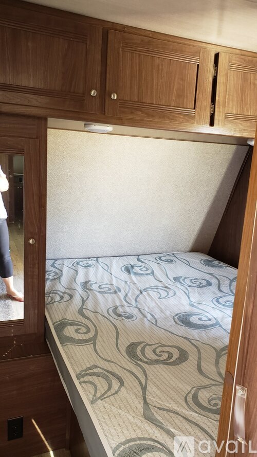 A bed with a blue and white patterned comforter is in a small room.