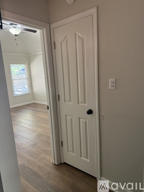 A white door is in a room with a fan and a window.