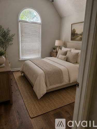 A bedroom with a large bed and a window with blinds.