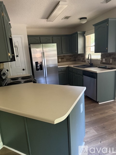 A kitchen with green cabinets and a white counter.
