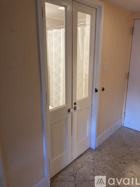 A white door with a glass window is in a room with a tiled floor.