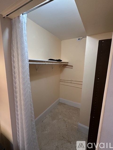 A small, empty room with a window covered by a sheer curtain.
