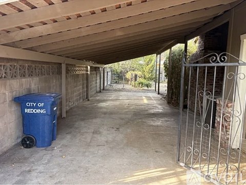 A long covered walkway with a blue trash can labeled City of Redding.