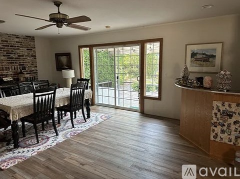 A dining room with a brick wall and a ceiling fan.