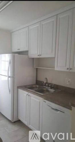 A kitchen with white cabinets and a refrigerator.