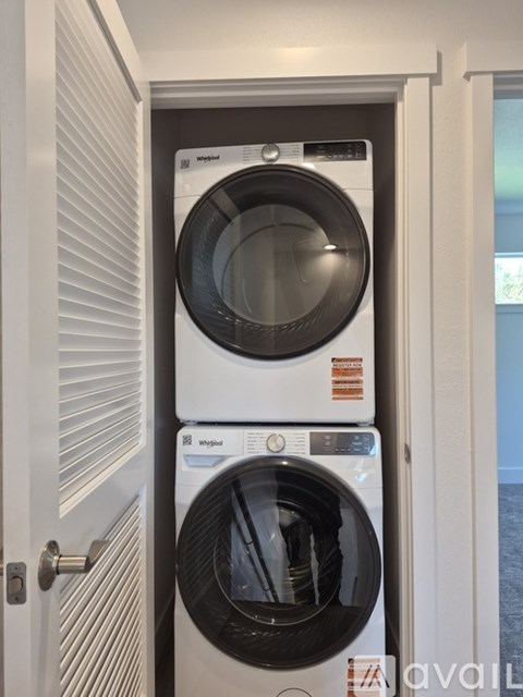 A stack of two Whirlpool washing machines in a laundry room.